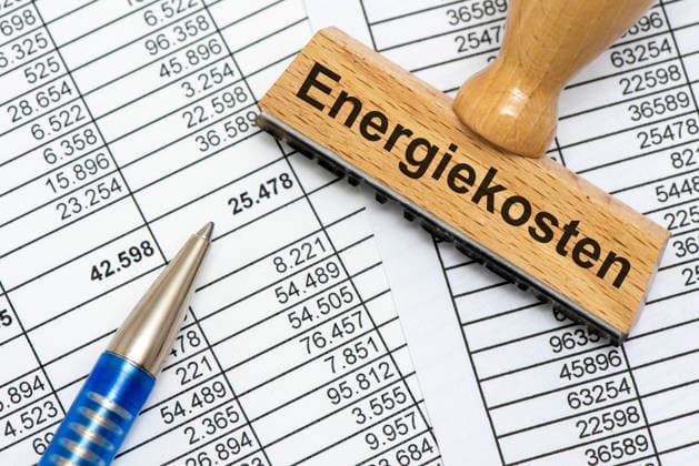 Energy Costs and Energy Prices: A wooden stamp bears the inscription Energy Costs as a symbolic image representing rising energy costs in business, industry, and commerce. PHOTOMONTAGE FOR EDITORIAL USE ONLY