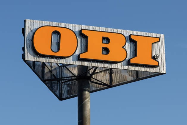 OBI Company Sign on a Pylon, Nuremberg, July 24, 2026: A company sign for the OBI home improvement store, visible from afar, mounted on a pylon against a blue sky. The orange-and-silver logo is the distinctive symbol of the home improvement store chain in Nuremberg, Bavaria, Germany. 20260724-286A2829-M4000
