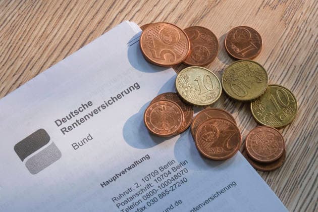 A close-up of a letterhead from the German Federal Pension Insurance Fund on a wooden surface, on which lies a small pile of euro cent coins (copper and brass coins). Nordrhein-Westfalen Deutschland, Germany 20260725-DSCF7792