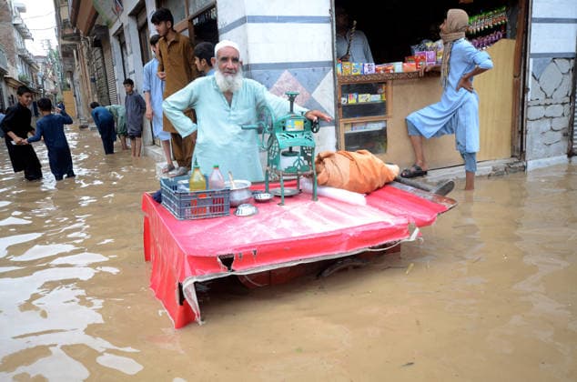 July 31, 2026, Peshawar, Peshawar, Pakistan: A merchant works as people wade through a flooded street during heavy monsoon rain in Peshawar, Khyber Pakhtunkhwa province, Pakistan. Pakistan s Meteorological Department (PMD) forecast the current monsoon spell to continue until August 5, warning of widespread rain, thunderstorms, heavy to very heavy downpours, and the risk of urban flooding, flash floods, landslides and river flooding across parts of the country. Peshawar Pakistan - ZUMAa217 20260731_znp_a217_029 Copyright: xHussainxAlix