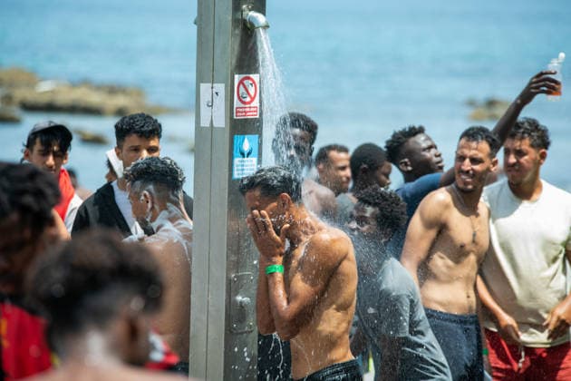 August 1, 2026, Ceuta, Ceuta, Spain: A group of migrants use beach showers near the Temporary Stay Centre for Immigrants Ceuta Spain - ZUMAd308 20260801_zsp_d308_083 Copyright: xJuanxCarlosxLucasx