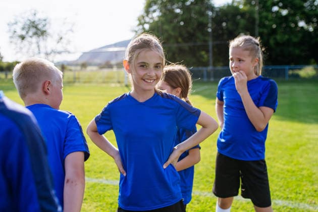 Mixed youth football team standing together on soccer field before training. Mixed youth football team standing together on soccer field before training session. model released
