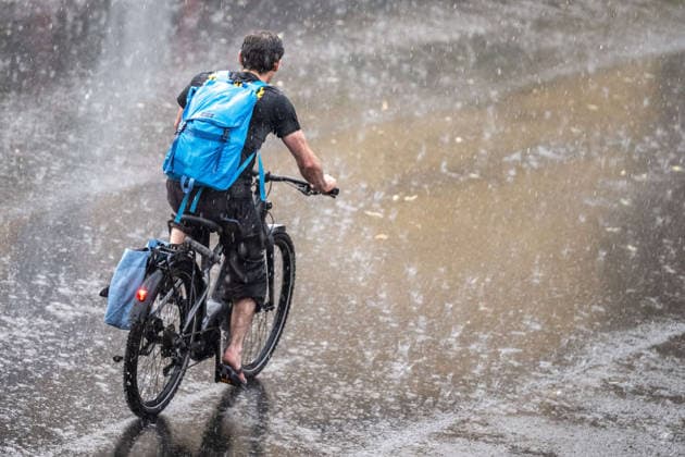 Heavy Rain in Göttingen, August 3, 2026; Göttingen: A cyclist rides down a street in Göttingen during a heavy rainstorm. Göttingen, Lower Saxony, Germany