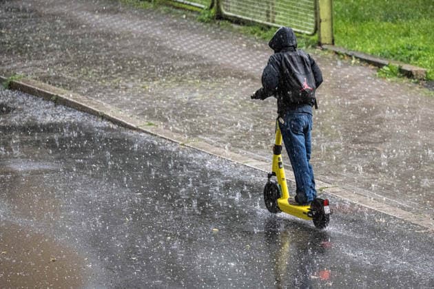 Heavy Rain in Göttingen, August 3, 2026, Göttingen: A man rides an e-scooter through Göttingen during a heavy rainstorm. Göttingen, Lower Saxony, Germany