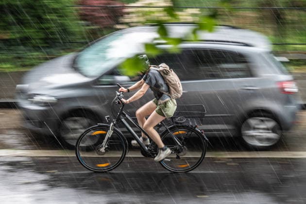 Heavy Rain in Göttingen, August 3, 2026; Göttingen: A cyclist rides down a street in Göttingen during a heavy rainstorm. Göttingen, Lower Saxony, Germany