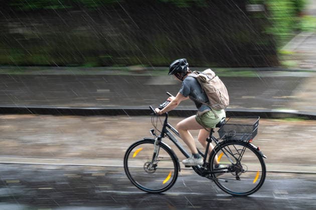 Heavy Rain in Göttingen, August 3, 2026; Göttingen: A cyclist rides down a street in Göttingen during a heavy rainstorm. Göttingen, Lower Saxony, Germany