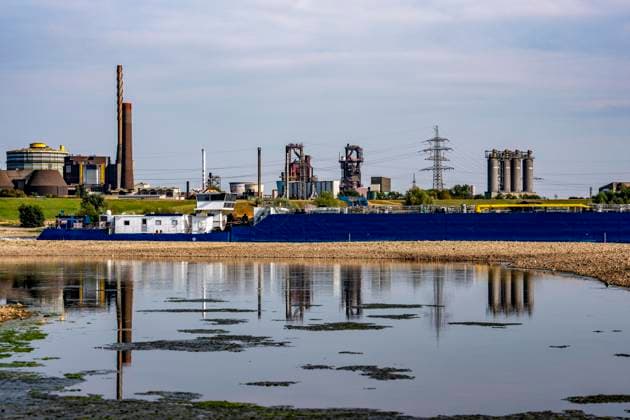 Extremely low water levels—here at the Thyssenkrupp Steel plant in Duisburg-Marxloh—have caused sandbars to form due to the low water level in the Rhine; cargo ships can only sail with reduced cargo; the TKS steel mill has cut back production because not enough raw