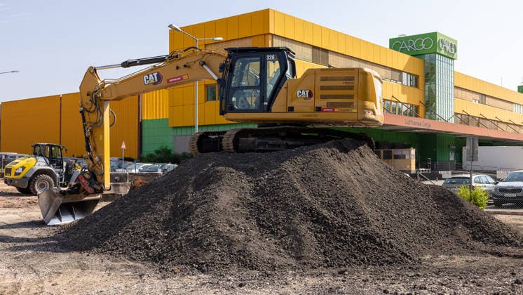 Start of Construction on Cargo Center 3 at Nuremberg Airport, Nuremberg, August 4, 2026 A CAT 326 chain excavator piles up excavated soil in front of the Lufthansa Cargo building, with another construction vehicle visible in the background. The photo shows the start of construction for the new Cargo Center 3 (CCN 3), with which the airport is responding to 20260804-286A4204-M4000