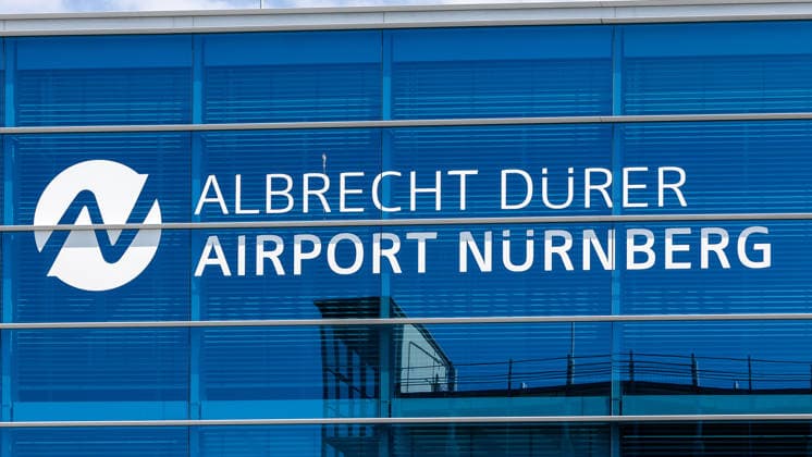 Nuremberg Airport, August 4, 2026 The sign reading Albrecht Dürer Airport Nuremberg is mounted on the glass facade of the airport building. The logo, featuring a stylized N, is visible on the blue-tinted window front. Nuremberg Airport, Bavaria, Germany 20260804-1V9A6679-M4000