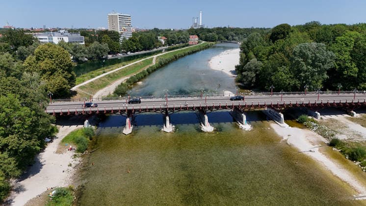 A summer day in Munich, the state capital. Here is a view of the Thalkirchner Bridge, a road bridge over the Isar River and the parallel Isar Werkkanal, which will be closed for two years starting in 2027 due to renovation, maintenance, traffic congestion, detours, neighborhoods, the zoo, and frustrated residents