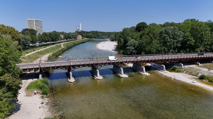 A summer day in Munich, the state capital. Here is a view of the Thalkirchner Bridge, a road bridge over the Isar River and the parallel Isar Werkkanal, which will be closed for two years starting in 2027 due to renovation, maintenance, traffic congestion, detours, neighborhoods, the zoo, and frustrated residents