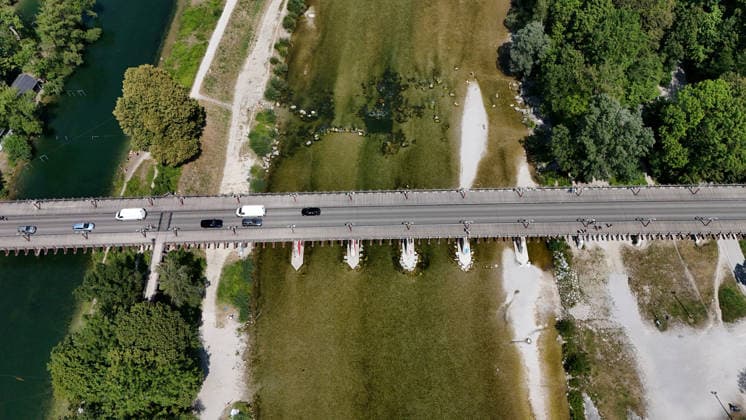 A summer day in Munich, the state capital. Here is a view of the Thalkirchner Bridge, a road bridge over the Isar River and the parallel Isar Werkkanal, which will be closed for two years starting in 2027 due to renovation, maintenance, traffic congestion, detours, neighborhoods, the zoo, and frustrated residents