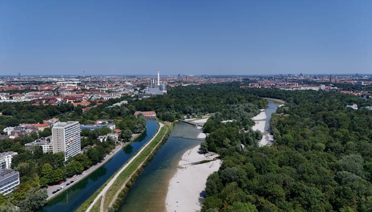 A summer day in Munich, the state capital. Here is a view of the Isar River and the Isar Werkskanal, as well as the Flaucher—a swimming area with a gravel beach—and the Munich skyline looking north: cityscape, sea of buildings, recreational area, sunbathing, swimming, cooling off