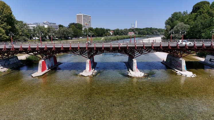 A summer day in Munich, the state capital. Here is a view of the Thalkirchner Bridge, a road bridge over the Isar River and the parallel Isar Werkkanal, which will be closed for two years starting in 2027 due to renovation, maintenance, traffic congestion, detours, neighborhoods, the zoo, and frustrated residents