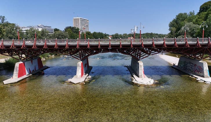 A summer day in Munich, the state capital. Here is a view of the Thalkirchner Bridge, a road bridge over the Isar River and the parallel Isar Werkkanal, which will be closed for two years starting in 2027 due to renovation, maintenance, traffic congestion, detours, neighborhoods, the zoo, and frustrated residents