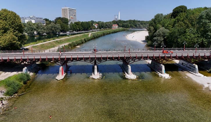 A summer day in Munich, the state capital. Here is a view of the Thalkirchner Bridge, a road bridge over the Isar River and the parallel Isar Werkkanal, which will be closed for two years starting in 2027 due to renovation, maintenance, traffic congestion, detours, neighborhoods, the zoo, and frustrated residents