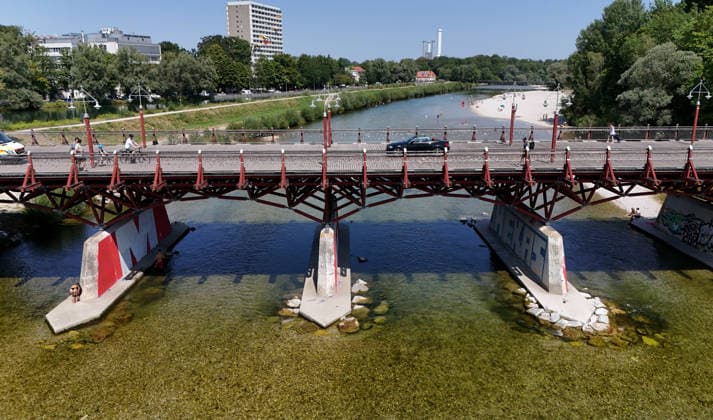 A summer day in Munich, the state capital. Here is a view of the Thalkirchner Bridge, a road bridge over the Isar River and the parallel Isar Werkkanal, which will be closed for two years starting in 2027 due to renovation, maintenance, traffic congestion, detours, neighborhoods, the zoo, and frustrated residents
