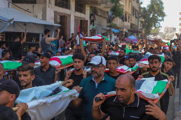 Gaza City Mass Funeral August 3 2026 Mourners carry bodies wrapped in Palestinian flags on stretchers during a mass funeral procession in the Al-Sabra neighborhood of Gaza City, Gaza Strip, on August 4, 2026. The remains of 112 members of the Abu Sharia and Al-Hasayneh families were recovered from the rubble of their home following an Israeli strike. Relatives stated the attack claimed the lives of more than 300 people. The bodies were buried at Al-Maamadani Cemetery as military operations continue across the territory. Gaza Gaza Strip Palestinian Territories Copyright: xRamezxHabboubx