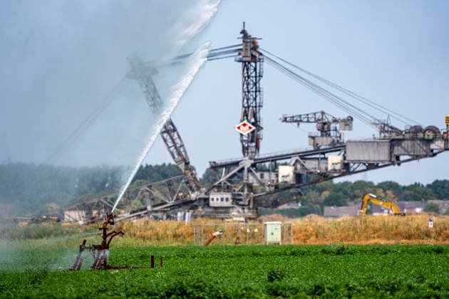 Artificial irrigation of a carrot field using a sprinkler system; a prolonged summer drought makes this necessary to ensure the harvest, near Erkelenz-Holzweiler, at the Garzweiler open-pit lignite mine, lignite excavators, North Rhine-Westphalia, Germany; Artificial irrigation