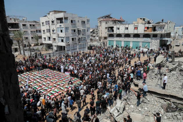 Gaza City Mass Funeral August 3 2026 Mourners gather around rows of bodies wrapped in Palestinian flags during a mass funeral procession in the Al-Sabra neighborhood of Gaza City, Gaza Strip, on August 4, 2026. The remains of 112 members of the Abu Sharia and Al-Hasayneh families were recovered from the rubble of their home following an Israeli strike. Relatives stated the attack claimed the lives of more than 300 people. The bodies were buried at Al-Maamadani Cemetery as military operations continue across the territory. Gaza Gaza Strip Palestinian Territories Copyright: xEyadxAzamx