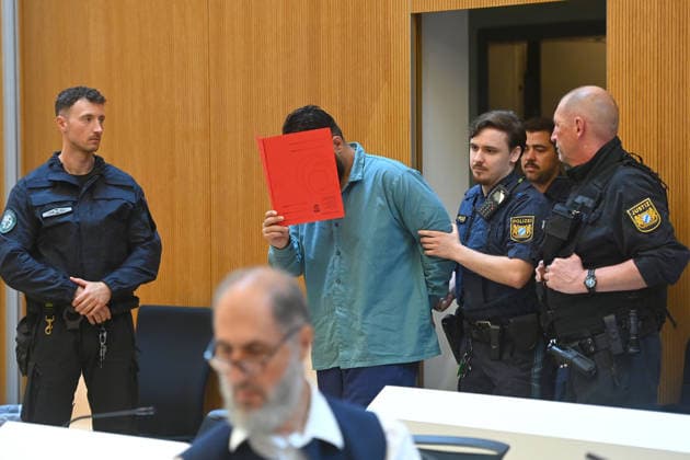 The defendant is escorted into the courtroom by court officers. The verdict in the criminal case against Farhad Noori for murder, among other charges, related to the Seidlstrasse incident will be handed down on August 6, 2026, at the Munich Higher Regional Court.