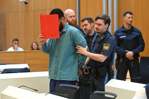 The defendant is escorted into the courtroom by court officers. The verdict in the criminal case against Farhad Noori for murder, among other charges, related to the Seidlstrasse incident will be handed down on August 6, 2026, at the Munich Higher Regional Court.
