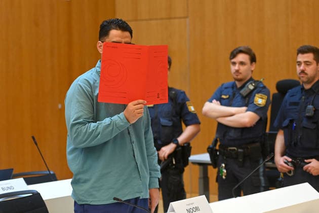 The defendant in the courtroom hides his face behind a binder. Judgment in the criminal case against Farhad Noori for murder, among other charges, on Seidlstrasse on August 6, 2026, before the Munich Higher Regional Court