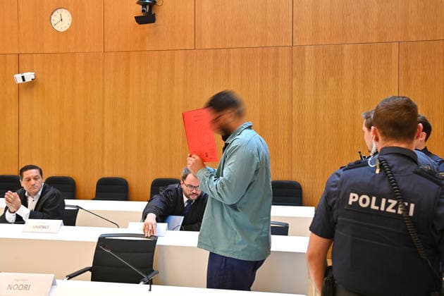The defendant in the courtroom hides his face behind a binder. Judgment in the criminal case against Farhad Noori for murder, among other charges, on Seidlstrasse on August 6, 2026, before the Munich Higher Regional Court
