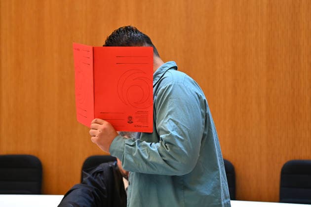 The defendant in the courtroom hides his face behind a binder. Judgment in the criminal case against Farhad Noori for murder, among other charges, on Seidlstrasse on August 6, 2026, before the Munich Higher Regional Court