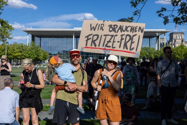 Fridays for Future Berlin Heat Protest, Germany, Berlin, August 6, 2026. A family—parents and a small child—hold up a sign reading We Need Fritze Frei. In front of the Chancellery, climate activists protest under the slogan The Climate Crisis Is Escalating, Chancellor Remains Silent. T