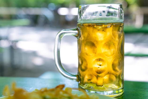 Germany, Bavaria, Munich - August 5, 2026: Two beer mugs and a snack (Käsespatzen) on a table in a beer garden. The image symbolizes Bavarian beer garden culture, conviviality, and traditional cuisine in Munich and Bavaria.