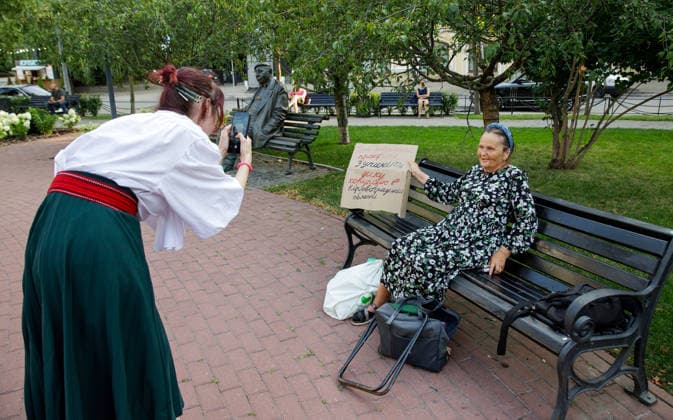 A woman in a traditional folk costume takes a picture of an elderly woman sitting on a bench with a placard during a peaceful protest against the dismissal of Mykhailo Fedorov from the post of Ukraine’s Defence Minister in Ivana Franka Square outside the Ivan Franko National Academic Drama Theatre, close to the Office of the President, Kyiv, Ukraine, August 6, 2026. Large-scale cardboard rallies in support of former Defence Minister Mykhailo Fedorov have been held in Kyiv and other cities across Ukraine for 22 consecutive days. On 14 July 2026, the Ukrainian Parliament accepted the resignation of Prime Minister Yuliia Svyrydenko, leading to the resignation of the Cabinet. On 15 July 2026, President Volodymyr Zelenskyy dismissed Defence Mi  Copyright: xMariannaxKotykx