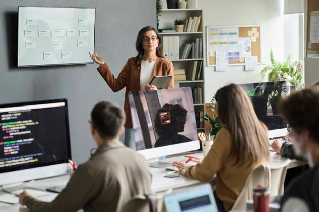 Female teacher explains programming to student group in classroom model released, Symbolfoto property released, DSHF02882