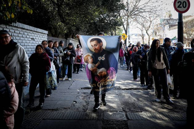 San Cayetano in Buenos Aires, Argentina - 7 Aug 2026 A devotee holds a giant banner with the image of San Cayetano during the feast of San Cayetano. Small prayer cards bearing the saint s image and stalks of wheat—representing bread—are a common sight every August 7th, the feast day of San Cayetano, the patron saint of bread and work. Buenos Aires Argentina Copyright: xRobertoxTuerox xSOPAxImagesx ROBTUERO_20260807284