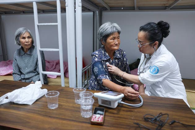 (260808) -- WUYI, Aug. 8, 2026 -- A doctor conducts health check for a villager at a temporary shelter in Datian Township, Wuyi County, Jinhua City, east China s Zhejiang Province, Aug. 8, 2026. The shelter has received 92 villagers, offering health check, meal delivery and other daily service. Coastal areas of eastern China were bracing for strong winds and torrential rain as Typhoon Dolphin approached, prompting authorities to recall fishing boats, suspend ferry services and prepare for evacuations. China s meteorological authority on Saturday upgraded its emergency response for Dolphin to Level III and raised the typhoon warning from yellow to orange. ) CHINA-ZHEJIANG-TYPHOON DOLPHIN-PREVENTION (CN) XuxYu