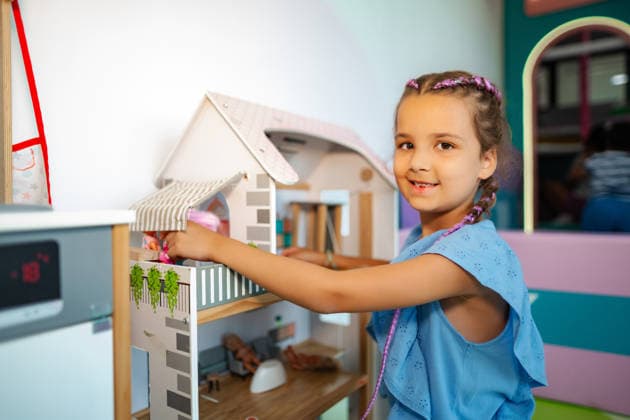 Ein kleines Mädchen spielt lächelnd mit einem Puppenhaus in einem Zimmer Young girl smiling during playtime, arranging dolls inside a toy dollhouse (License=RF) ,model released, Symbolfoto Copyright: xZoonar.com JelenaxCvetkovicx 25376976 ,model released, Symbolfoto ,property released