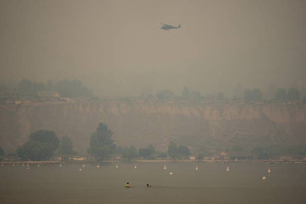 August 9, 2026, Penticton, Bc, CANADA: People float in the water while a helicopter being used to battle wildfires flies overhead as smoke from the Bald Range wildfire envelops Okanagan Lake, in Penticton, B.C., on Sunday, Aug. 9, 2026. The Bald Range wildfire in British Columbia s south Okanagan region has forced 20,000 people out of their homes in the Peachland and Summerland areas. Penticton CANADA - ZUMAc35_ 20260809_zaf_c35_057 Copyright: xDarrylxDyckx