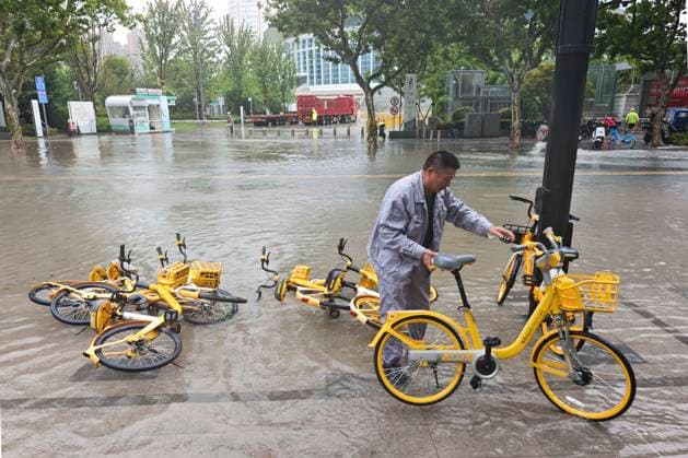 SHANGHAI, CHINA - AUGUST 09: Maintenance workers right shared bicycles knocked down by wind and rain amidst flooding caused by Typhoon Dolphin on August 9, 2026 in Shanghai, China. The city experienced severe weather conditions as the typhoon made landfall bringing heavy rainfall and strong winds.  Copyright: xVCGx 111659005865