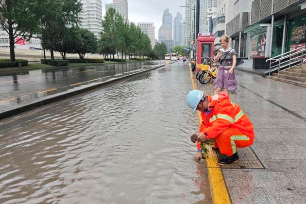 SHANGHAI, CHINA - AUGUST 09: A sanitation worker clears debris from a drainage outlet on Caoxi North Road to accelerate waterlogging relief as Typhoon Dolphin brings heavy rainfall on August 9, 2026 in Shanghai, China.  Copyright: xVCGx 111659005872