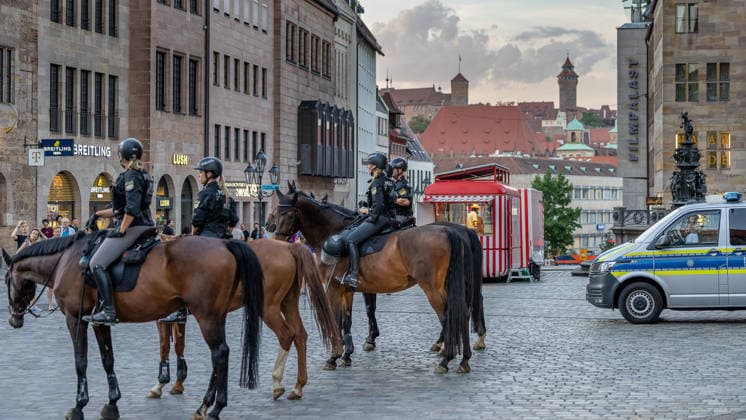 Police operation during the Monday demonstration by Team Menschenrechte and counter-protests, Nuremberg, 10 087 2026 Mounted police units secure the scene at Lorenzerplatz. In the background are Nuremberg Castle, historic buildings, and a police emergency vehicle. Nuremberg, Bavaria, Germany 20260810-286A5051-M4000