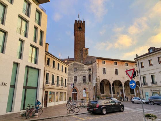 Menschen auf der Straße vor dem Rathausturm in Treviso TREVISO, ITALY - SEPT 10, 2025: A city street with parked vehicles and a modern building featuring a historic Torre Civica clock tower in Treviso, Italy. (License=RF) Copyright: xZoonar.com IvanxTykhyix 25426908