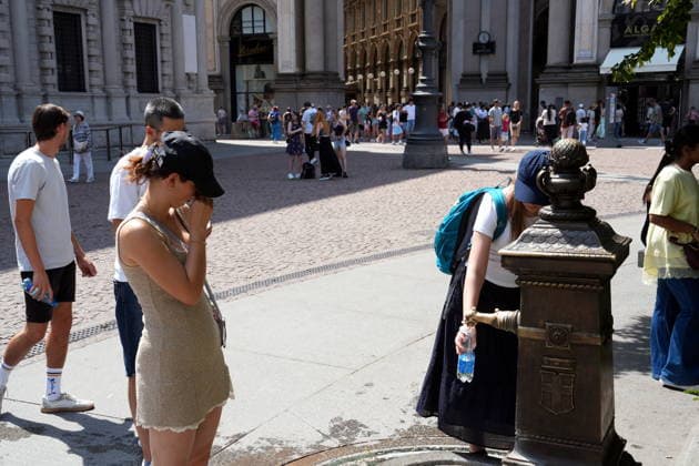 IPA87397509 - Milan, August 11, 2026: It’s hot in Milan. The heat wave continues, and tourists are shielding themselves from the sun with clothing, umbrellas, and hats, and are cooling off or drinking water at the fountain in Piazza Scala.  Copyright: xDuilioxPiaggesix xDuilioxPiaggesix 87397509