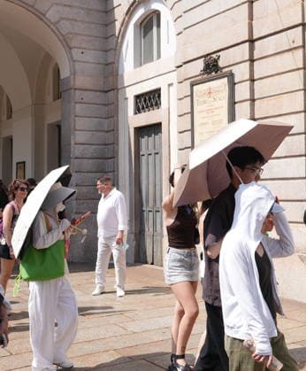 IPA87397518 - Milan, August 11, 2026: It’s hot in Milan. The heat wave continues, and tourists are shielding themselves from the sun with clothing, umbrellas, and hats, and are cooling off or drinking water at the fountain in Piazza Scala.  Copyright: xDuilioxPiaggesix xDuilioxPiaggesix 87397518