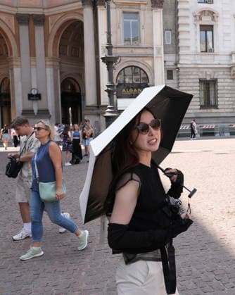 IPA87397522 - Milan, August 11, 2026: It’s hot in Milan. The heat wave continues, and tourists are shielding themselves from the sun with clothing, umbrellas, and hats, and are cooling off or drinking water at the fountain in Piazza Scala.  Copyright: xDuilioxPiaggesix xDuilioxPiaggesix 87397522