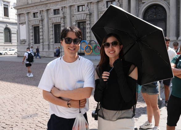 IPA87397540 - Milan, August 11, 2026: It’s hot in Milan. The heat wave continues, and tourists are shielding themselves from the sun with clothing, umbrellas, and hats, and are cooling off or drinking water at the fountain in Piazza Scala.  Copyright: xDuilioxPiaggesix xDuilioxPiaggesix 87397540