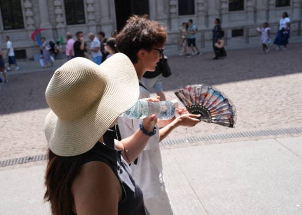 IPA87397537 - Milan, August 11, 2026: It’s hot in Milan. The heat wave continues, and tourists are shielding themselves from the sun with clothing, umbrellas, and hats, and are cooling off or drinking water at the fountain in Piazza Scala.  Copyright: xDuilioxPiaggesix xDuilioxPiaggesix 87397537