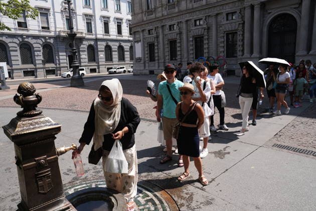 IPA87397538 - Milan, August 11, 2026: It’s hot in Milan. The heat wave continues, and tourists are shielding themselves from the sun with clothing, umbrellas, and hats, and are cooling off or drinking water at the fountain in Piazza Scala.  Copyright: xDuilioxPiaggesix xDuilioxPiaggesix 87397538
