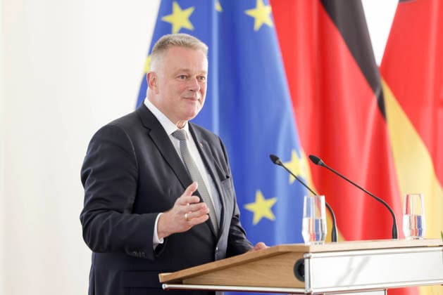 Prime Minister Gordon Schnieder at the lectern in front of flags during a ceremony to confer professional titles at the State Chancellery of Rhineland-Palatinate, August 26, 2011
