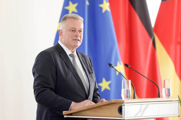 Prime Minister Gordon Schnieder at the lectern in front of flags during a ceremony to confer professional titles at the State Chancellery of Rhineland-Palatinate, August 26, 2011