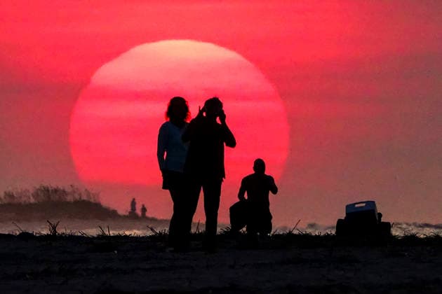 August 12, 2026, Isle Of Palms, Sc, United States: People silhouetted by the sunrise, stop to watch as the massive ball climbs over the Atlantic Ocean horizon, August 12, 2026 in Isle of Palms, South Carolina. The Charleston area is currently under a heat advisory with temperatures in the 90Ã¢â‚¬â ¢s and a heat index of 115-degrees. Isle Of Palms United States - ZUMAe02_ 20260812_zaf_e02_001 Copyright: xRichardxEllisx